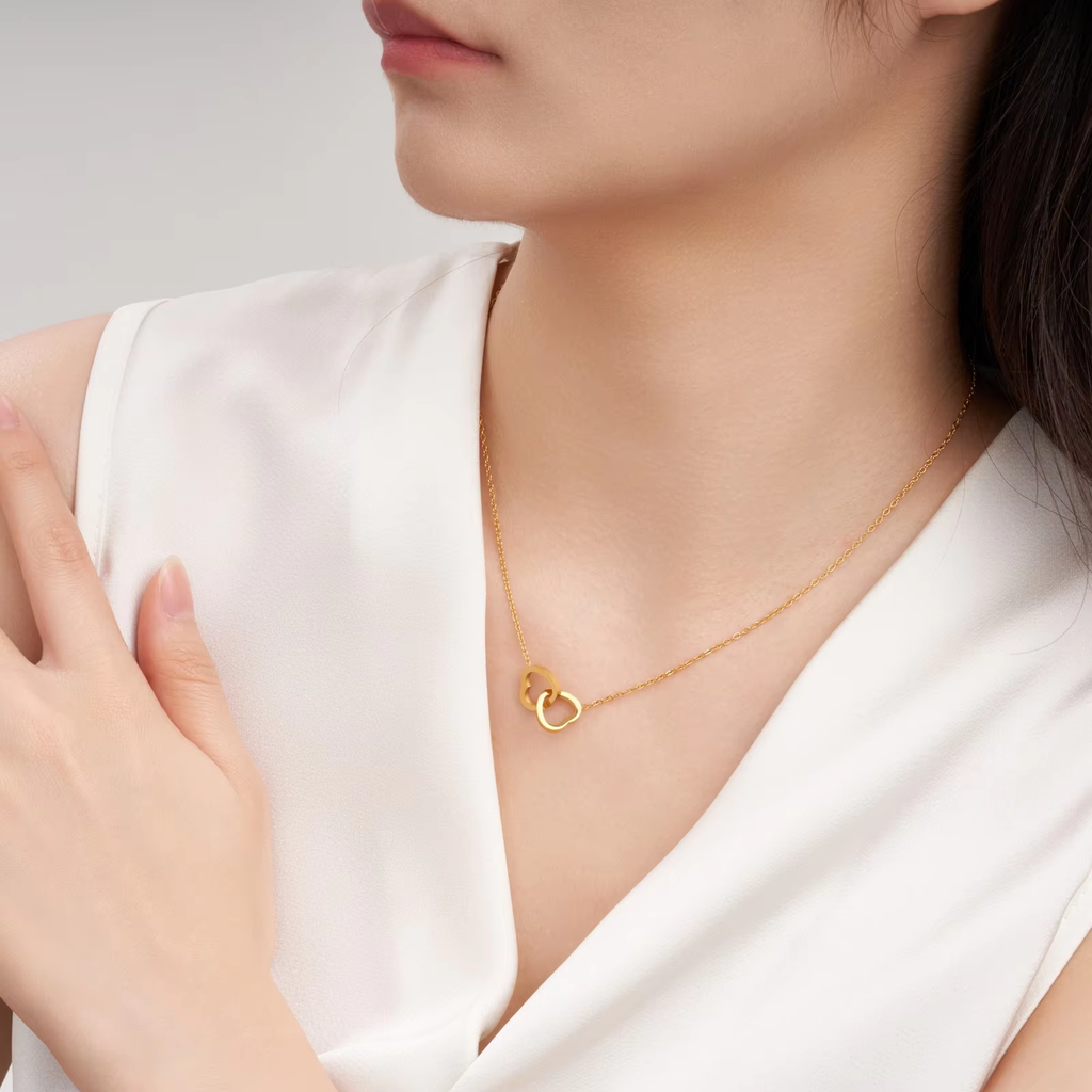 Stainless steel 18K gold PVD plated interlocking heart pendant necklace with minimalist geometric design on fine chain.