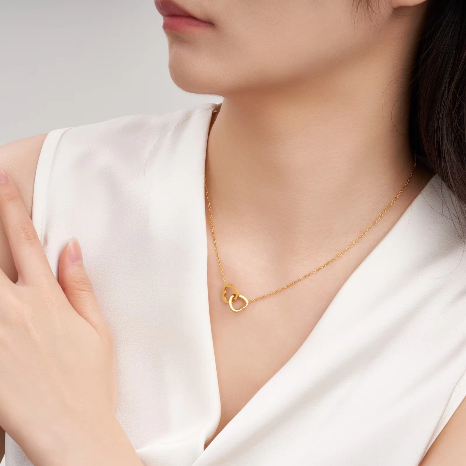 Stainless steel 18K gold PVD plated interlocking heart pendant necklace with minimalist geometric design on fine chain.