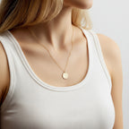 Gold stainless steel multilayer necklace with custom name pendant, bead chain, and textured disc charm displayed on a white surface.