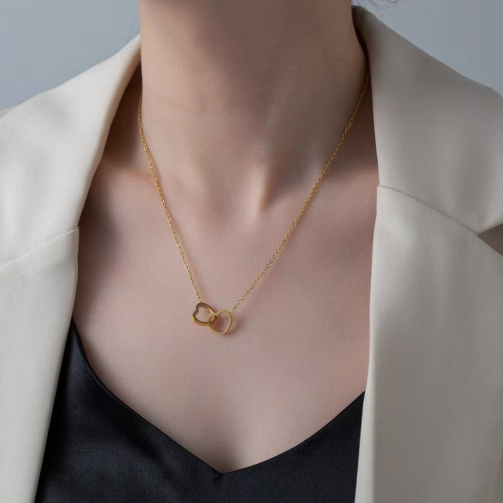 Stainless steel 18K gold PVD plated interlocking heart pendant necklace with minimalist geometric design on fine chain.