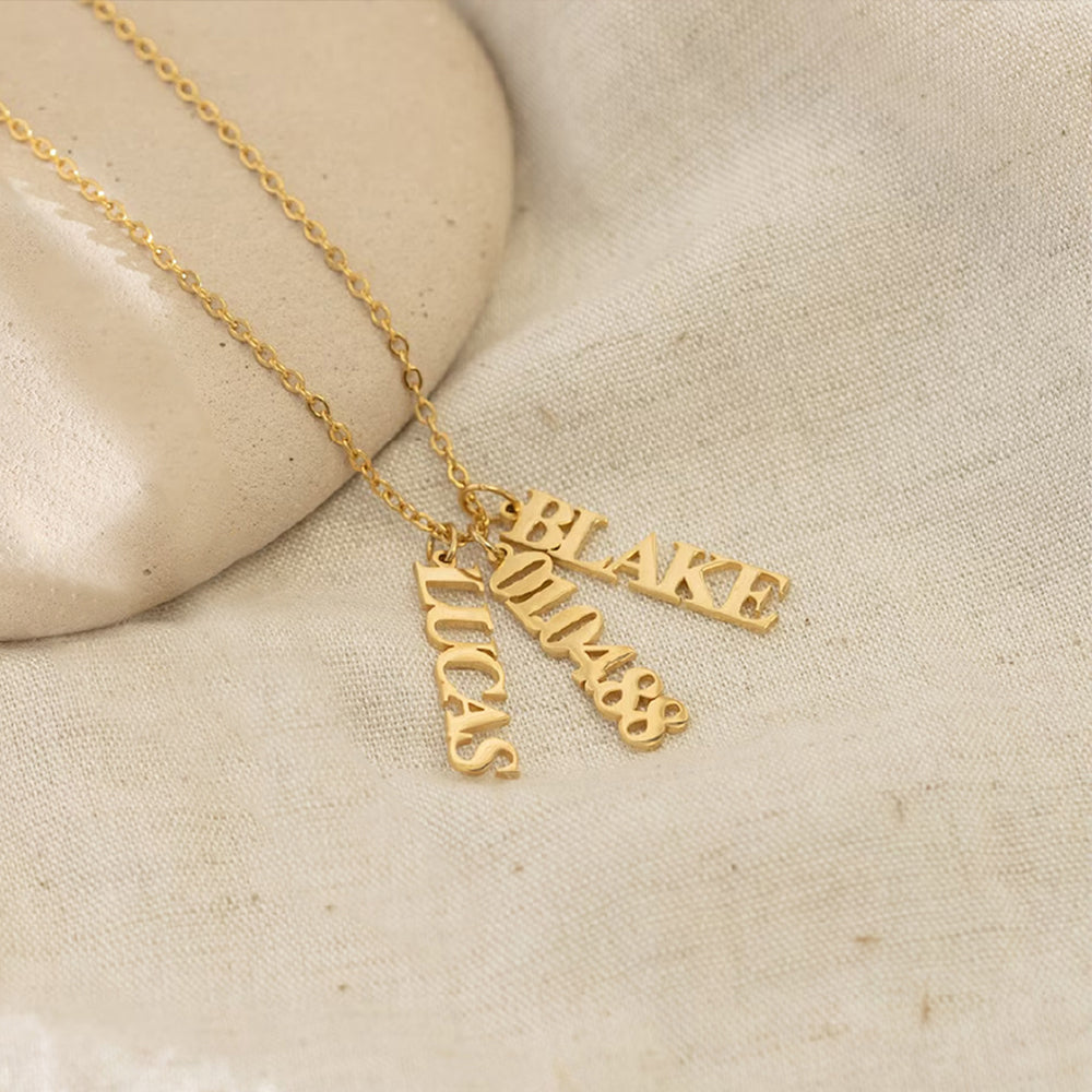 Personalized vertical name necklace in stainless steel with multiple custom name pendants, adjustable 40+5 cm chain, gold finish shown on model.