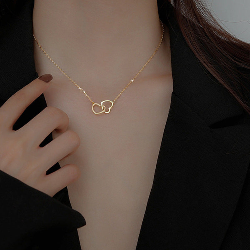 Stainless steel 18K gold PVD plated interlocking heart pendant necklace with minimalist geometric design on fine chain.
