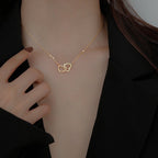 Stainless steel 18K gold PVD plated interlocking heart pendant necklace with minimalist geometric design on fine chain.
