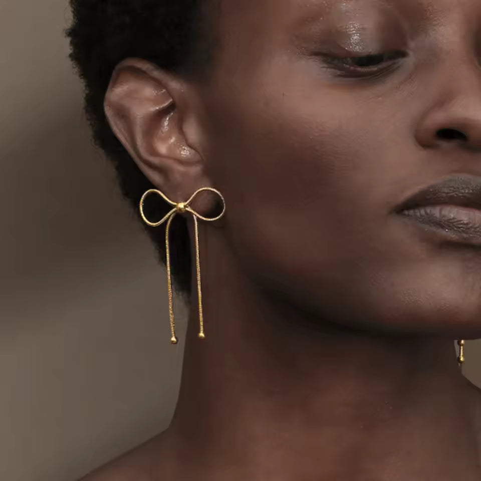 18K gold PVD plated stainless steel bow knot drop earrings with delicate chain design and polished bead accents for women