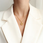 18K gold plated stainless steel water drop pendant necklace with concave geometric design and pearl accent, adjustable chain on white background