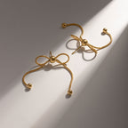 18K gold PVD plated stainless steel bow knot drop earrings with delicate chain design and polished bead accents for women