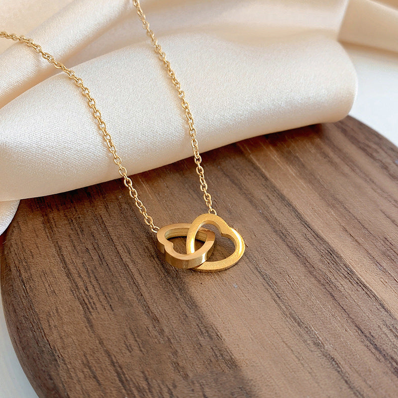Stainless steel 18K gold PVD plated interlocking heart pendant necklace with minimalist geometric design on fine chain.