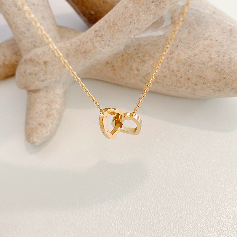 Stainless steel 18K gold PVD plated interlocking heart pendant necklace with minimalist geometric design on fine chain.