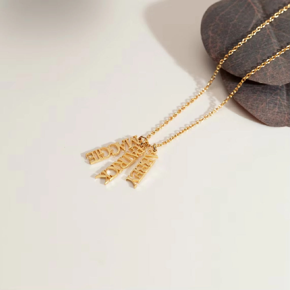 Personalized vertical name necklace in stainless steel with multiple custom name pendants, adjustable 40+5 cm chain, gold finish shown on model.