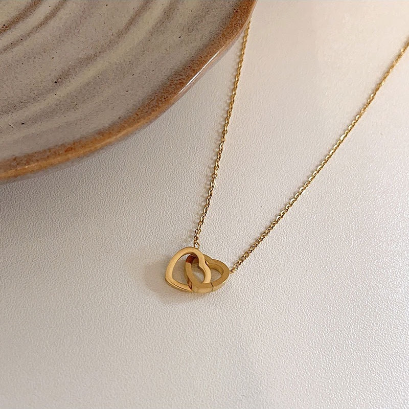Stainless steel 18K gold PVD plated interlocking heart pendant necklace with minimalist geometric design on fine chain.