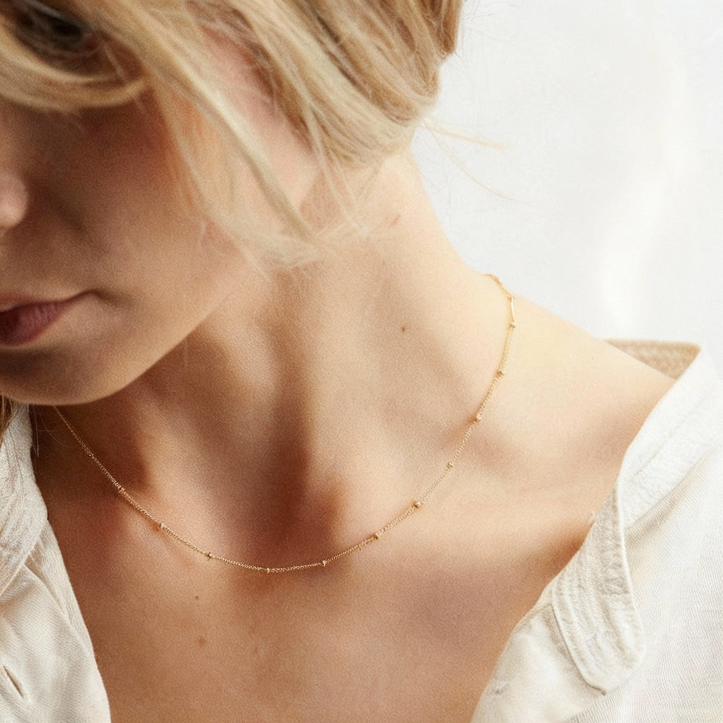 Gold stainless steel multilayer necklace with custom name pendant, bead chain, and textured disc charm displayed on a white surface.