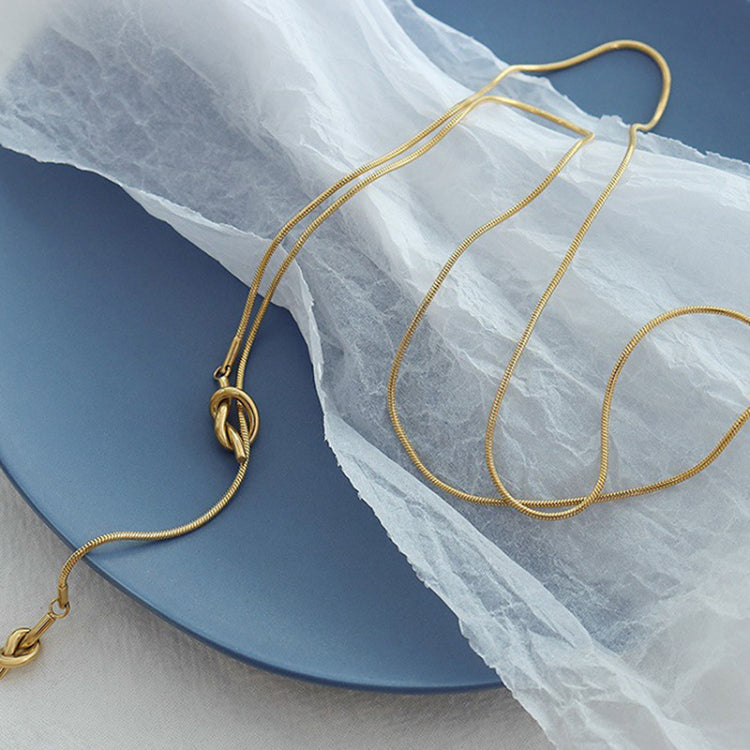 18K gold plated stainless steel knotted pendant necklace with long adjustable chain, geometric trendy women’s jewelry on white background