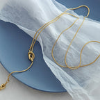 18K gold plated stainless steel knotted pendant necklace with long adjustable chain, geometric trendy women’s jewelry on white background