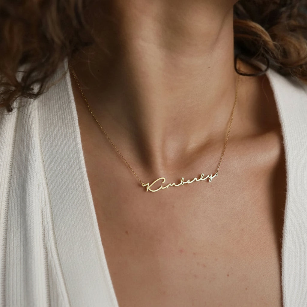 Gold stainless steel multilayer necklace with custom name pendant, bead chain, and textured disc charm displayed on a white surface.